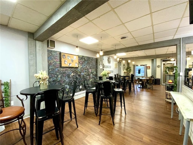 dining space featuring wood-type flooring and a paneled ceiling