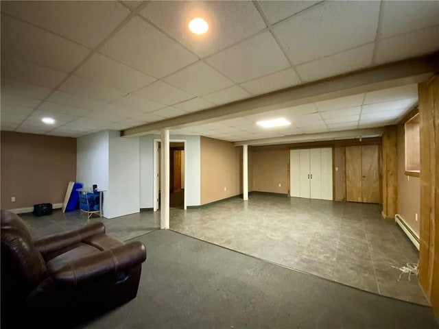 basement with a drop ceiling and baseboard heating