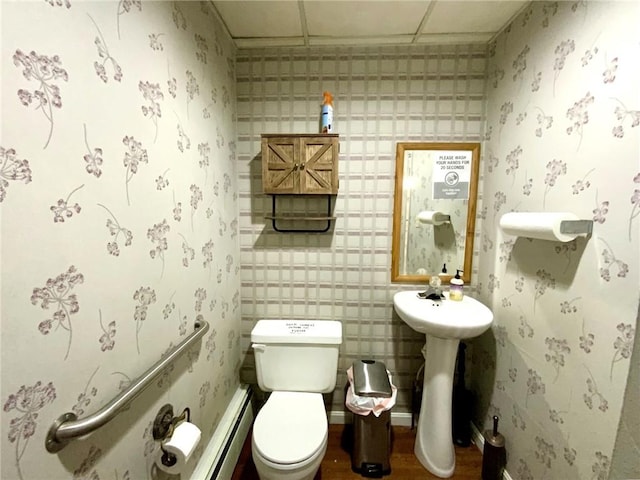 bathroom with hardwood / wood-style flooring, a baseboard heating unit, and toilet