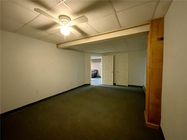 empty room featuring a paneled ceiling, ceiling fan, and dark colored carpet