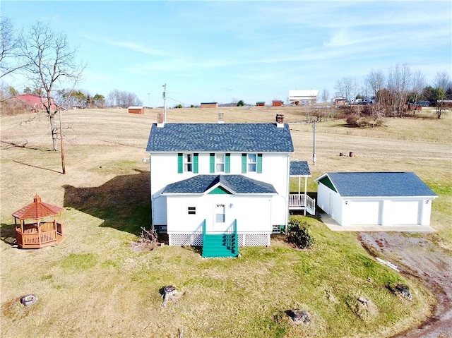 rear view of property with a garage, a gazebo, an outdoor structure, and a lawn