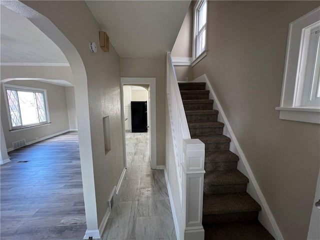 stairs featuring crown molding and wood-type flooring