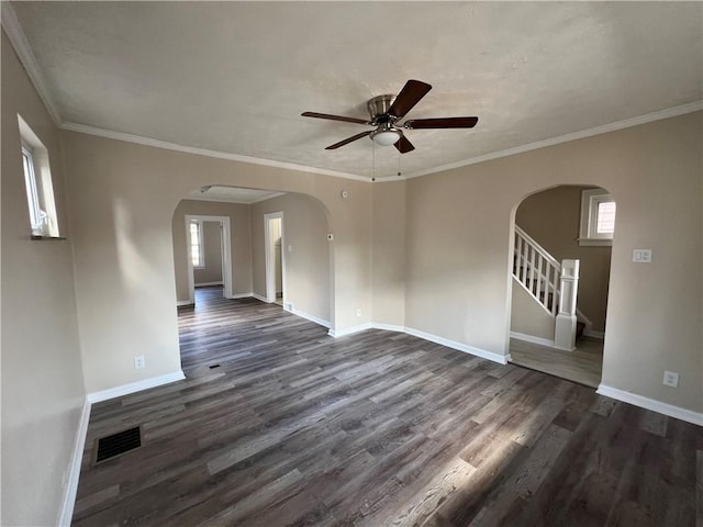 empty room with ornamental molding, a wealth of natural light, and dark hardwood / wood-style flooring