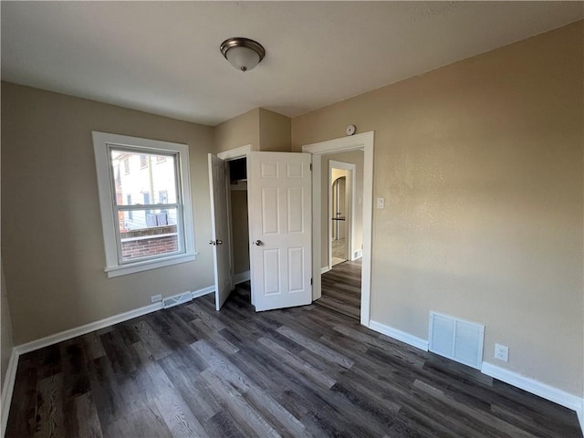 unfurnished bedroom with dark wood-type flooring and a closet