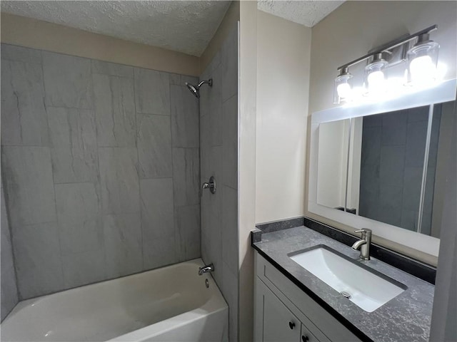 bathroom with tiled shower / bath, vanity, and a textured ceiling