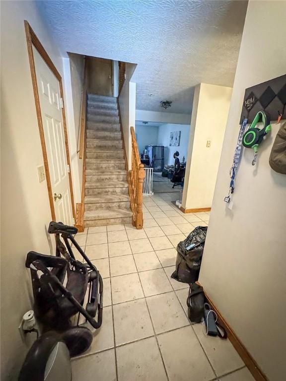 staircase with tile patterned floors and a textured ceiling