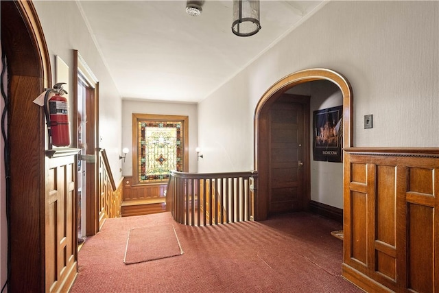 hallway featuring crown molding and dark carpet