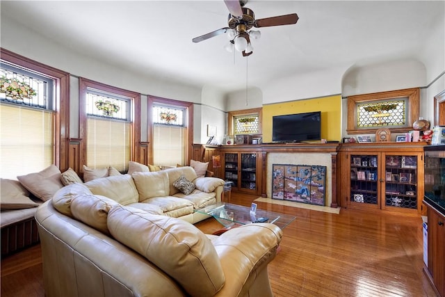 living room featuring hardwood / wood-style flooring, ceiling fan, and a fireplace