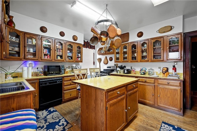 kitchen featuring light hardwood / wood-style floors, sink, black appliances, and a center island