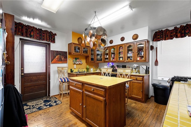 kitchen featuring hardwood / wood-style flooring, tile countertops, a kitchen island, and a notable chandelier