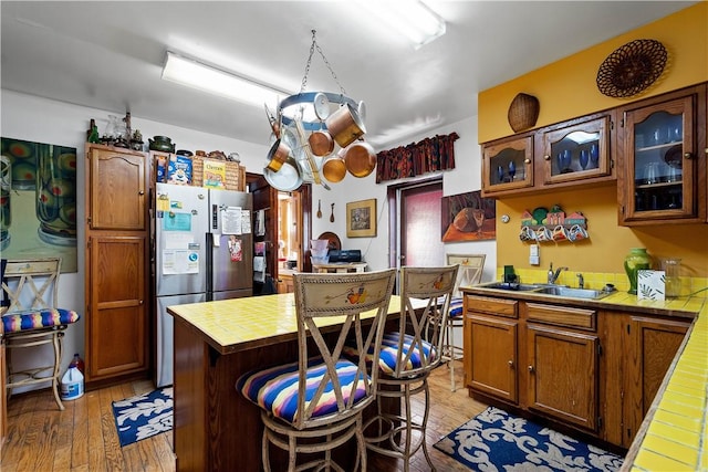 kitchen featuring light hardwood / wood-style flooring, sink, tile countertops, and stainless steel fridge