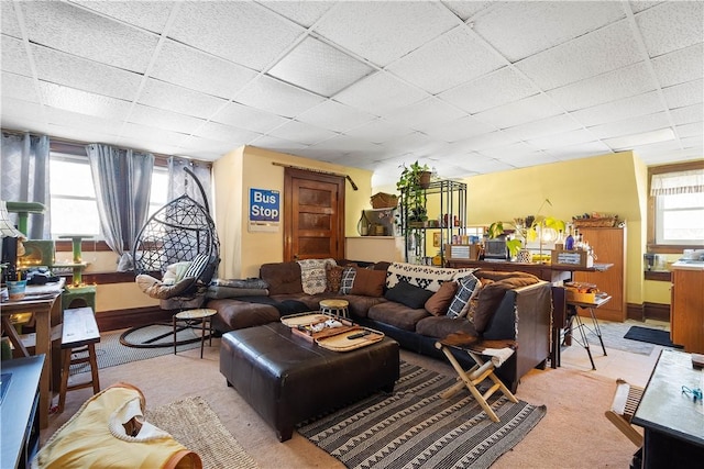 living room with a paneled ceiling and light colored carpet