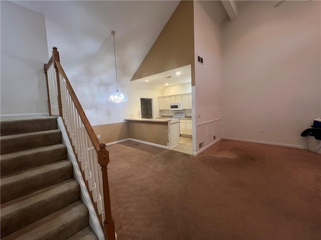 unfurnished living room featuring light carpet, a notable chandelier, and high vaulted ceiling