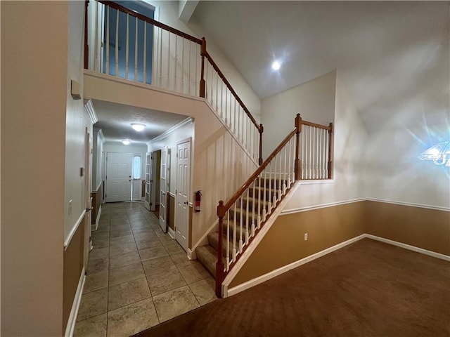 staircase featuring tile patterned floors, ornamental molding, and a high ceiling