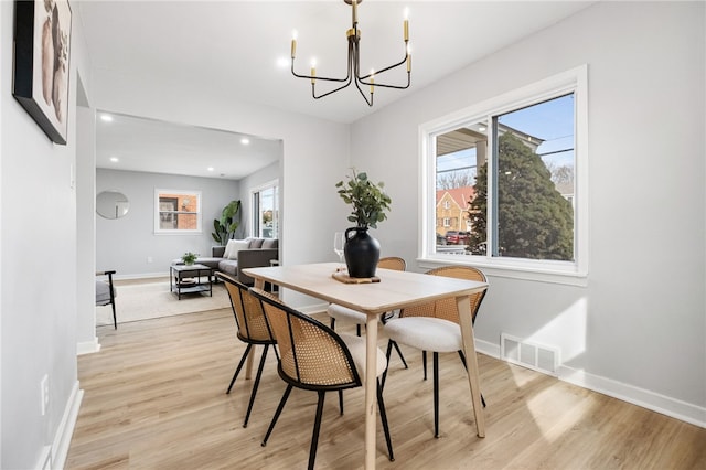 dining area with a wealth of natural light, a chandelier, and light hardwood / wood-style flooring