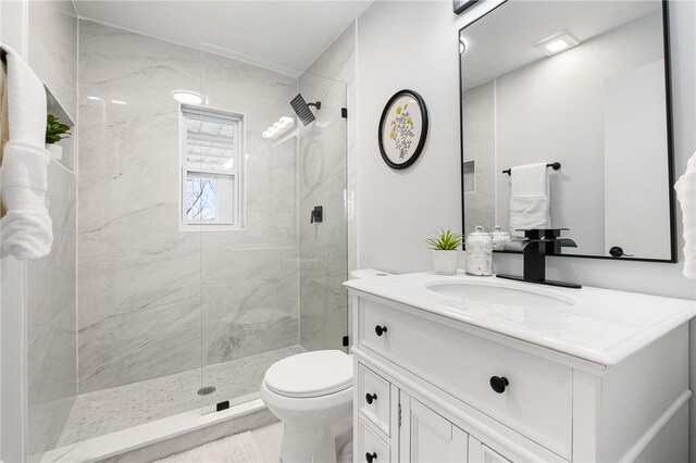 bathroom with vanity, toilet, and tiled shower