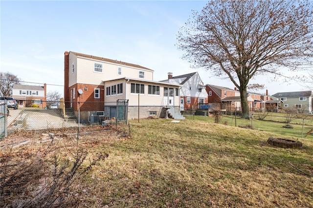 rear view of property with cooling unit, an outdoor fire pit, and a lawn