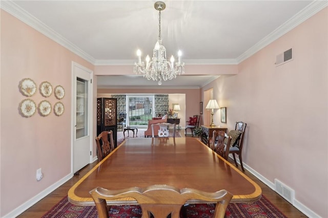 dining room featuring hardwood / wood-style flooring, ornamental molding, and a notable chandelier