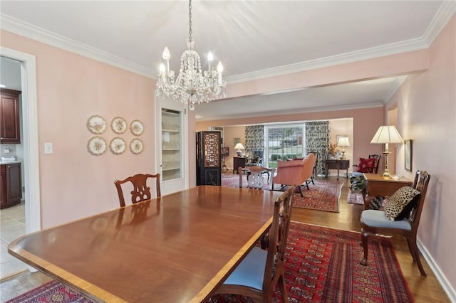 dining area with ornamental molding, a chandelier, and light wood-type flooring