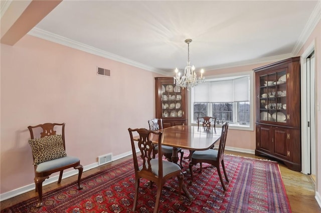 dining area with crown molding, hardwood / wood-style floors, and a chandelier