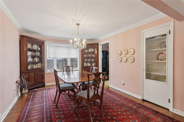 dining room with an inviting chandelier, hardwood / wood-style flooring, and ornamental molding