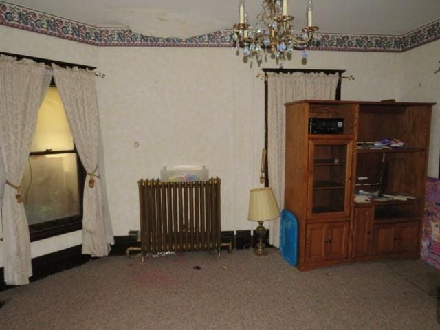 interior space featuring radiator, a chandelier, and dark colored carpet