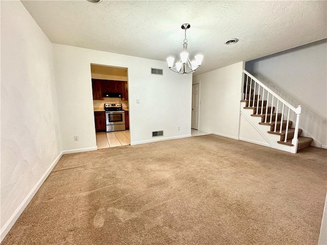 spare room featuring light carpet, a textured ceiling, and a chandelier