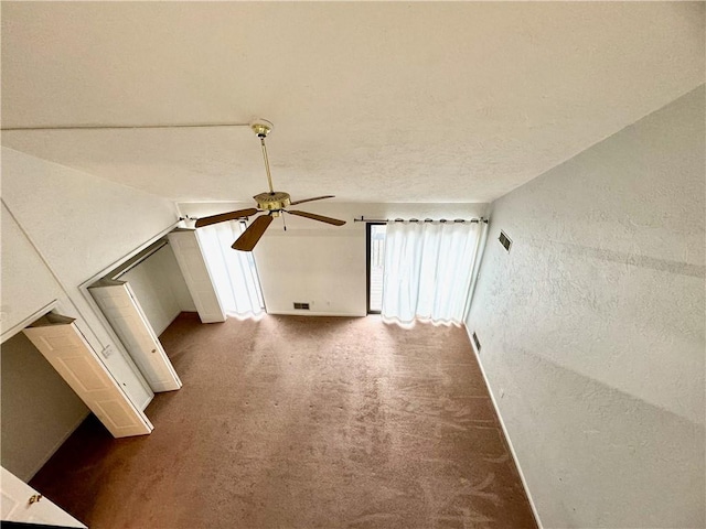 additional living space with ceiling fan, lofted ceiling, dark carpet, and a textured ceiling