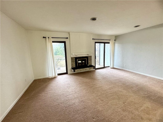 unfurnished living room featuring a fireplace, a healthy amount of sunlight, and carpet flooring