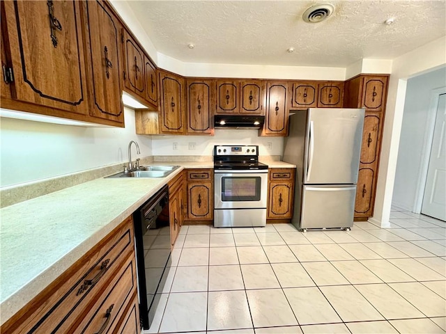 kitchen with appliances with stainless steel finishes, sink, a textured ceiling, and light tile patterned floors