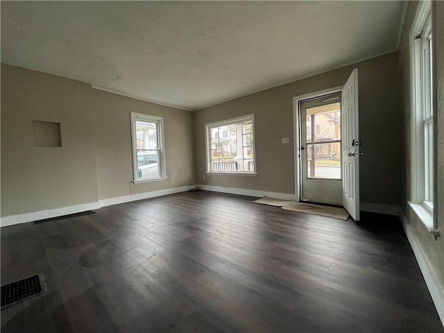 unfurnished room featuring a wealth of natural light and dark hardwood / wood-style floors