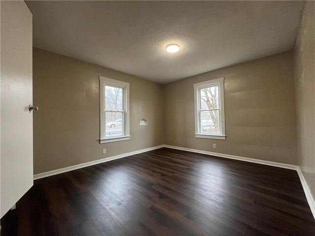 empty room featuring dark wood-type flooring and plenty of natural light