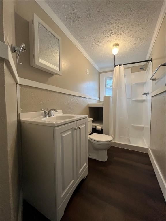 bathroom with crown molding, hardwood / wood-style floors, a textured ceiling, and a shower with shower curtain