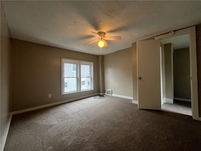 spare room with ceiling fan, a textured ceiling, and dark colored carpet