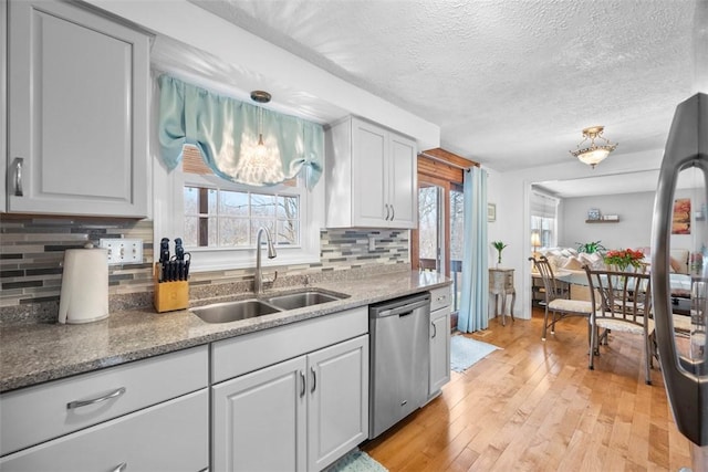 kitchen with sink, a textured ceiling, light hardwood / wood-style flooring, dishwasher, and backsplash