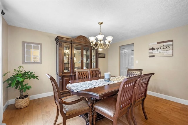 dining area featuring an inviting chandelier, wood-type flooring, and a textured ceiling