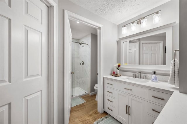 bathroom with hardwood / wood-style floors, an enclosed shower, vanity, a textured ceiling, and toilet