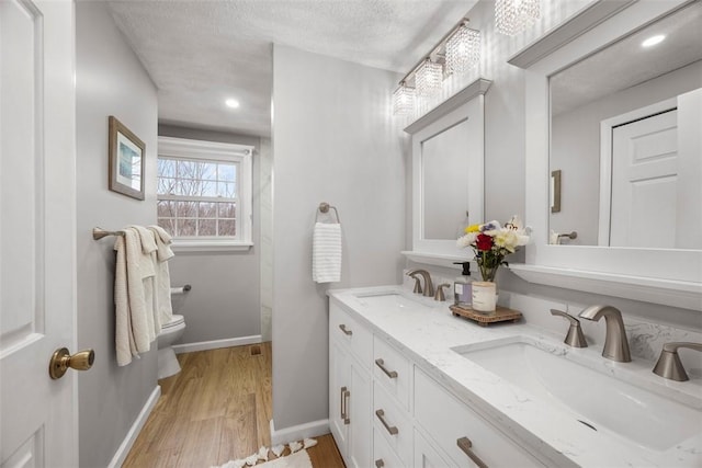 bathroom featuring vanity, hardwood / wood-style floors, a textured ceiling, and toilet