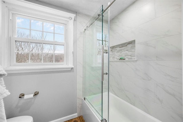 bathroom with shower / bath combination with glass door and toilet