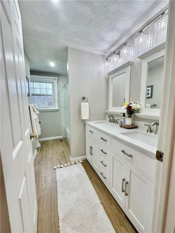 bathroom featuring wood-type flooring, an enclosed shower, vanity, and a textured ceiling