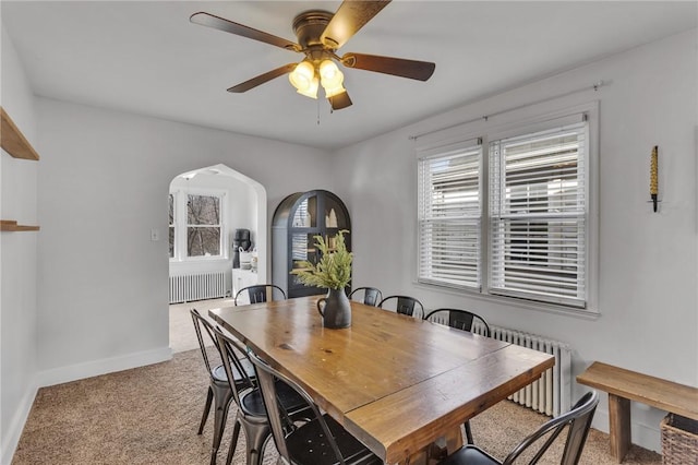 carpeted dining space with radiator heating unit and ceiling fan