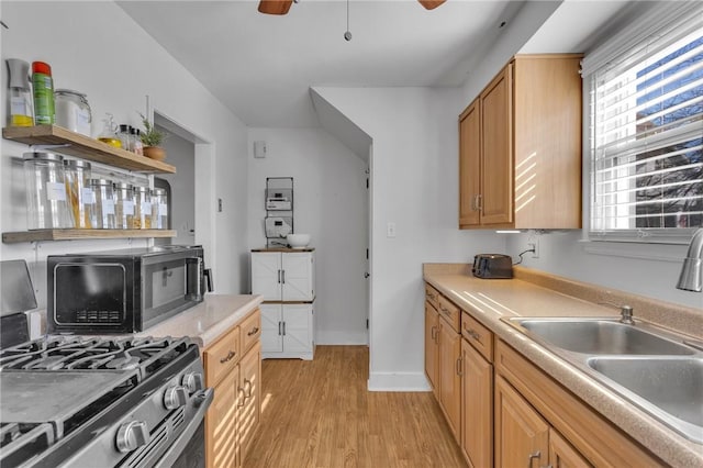 kitchen featuring sink, stainless steel gas range, ceiling fan, and light wood-type flooring