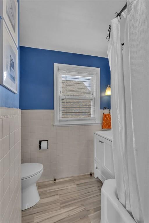 full bathroom with tile walls, vanity, toilet, and shower / bathtub combination with curtain