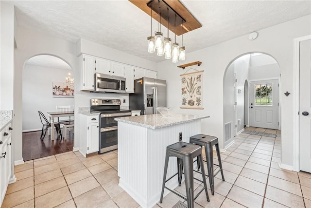530 Peregrine Dr, North Huntingdon, PA 15642 - kitchen with light tile patterned floors, stainless steel appliances, arched walkways, white cabinets, and a textured ceiling