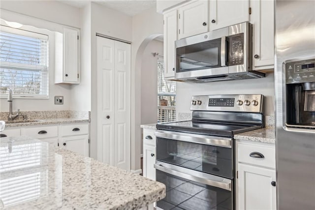 530 Peregrine Dr, North Huntingdon, PA 15642 - kitchen with a sink, stainless steel appliances, arched walkways, white cabinets, and light stone countertops