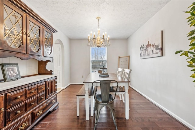 530 Peregrine Dr, North Huntingdon, PA 15642 - dining area featuring a notable chandelier, a textured ceiling, arched walkways, baseboards, and dark wood-style flooring