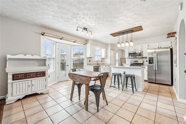 530 Peregrine Dr, North Huntingdon, PA 15642 - dining space with arched walkways, light tile patterned floors, a textured ceiling, and baseboards