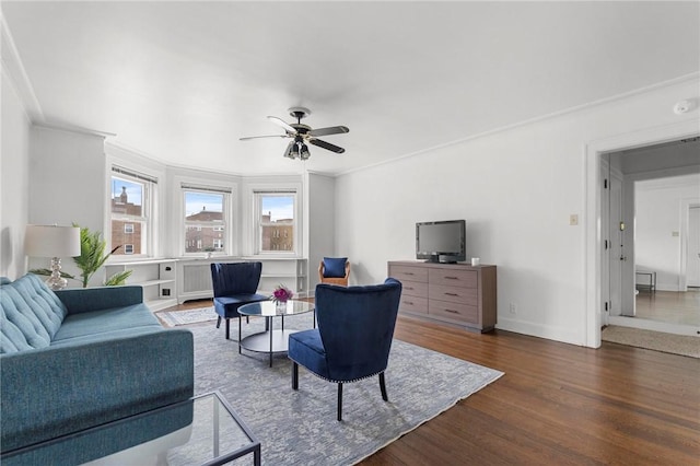 living room with dark hardwood / wood-style flooring, crown molding, and ceiling fan