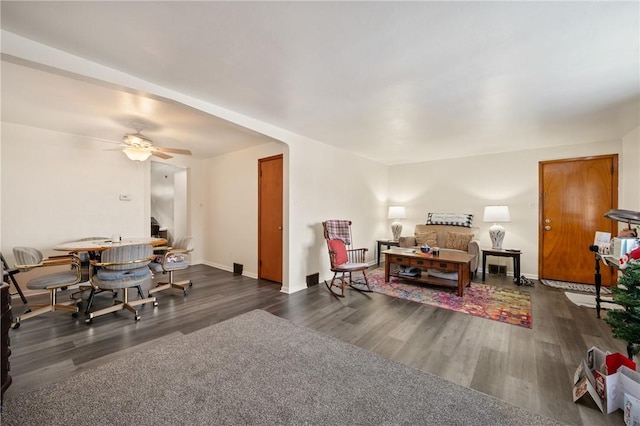 living room featuring dark wood-type flooring and ceiling fan