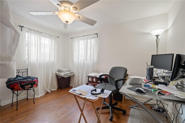 home office with light hardwood / wood-style floors and ceiling fan